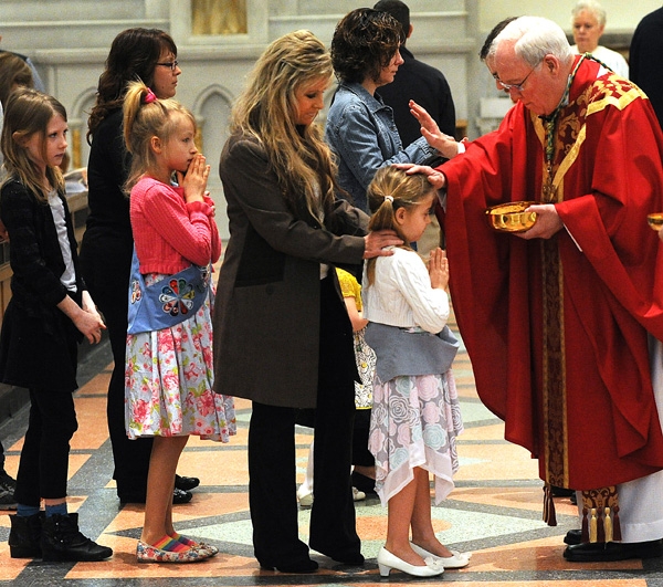 Bishop Richard Malone blessed a young girl during communion at St Joseph Cathedral on Palm Sunday. (Dan Cappellazzo/Staff Photographer)